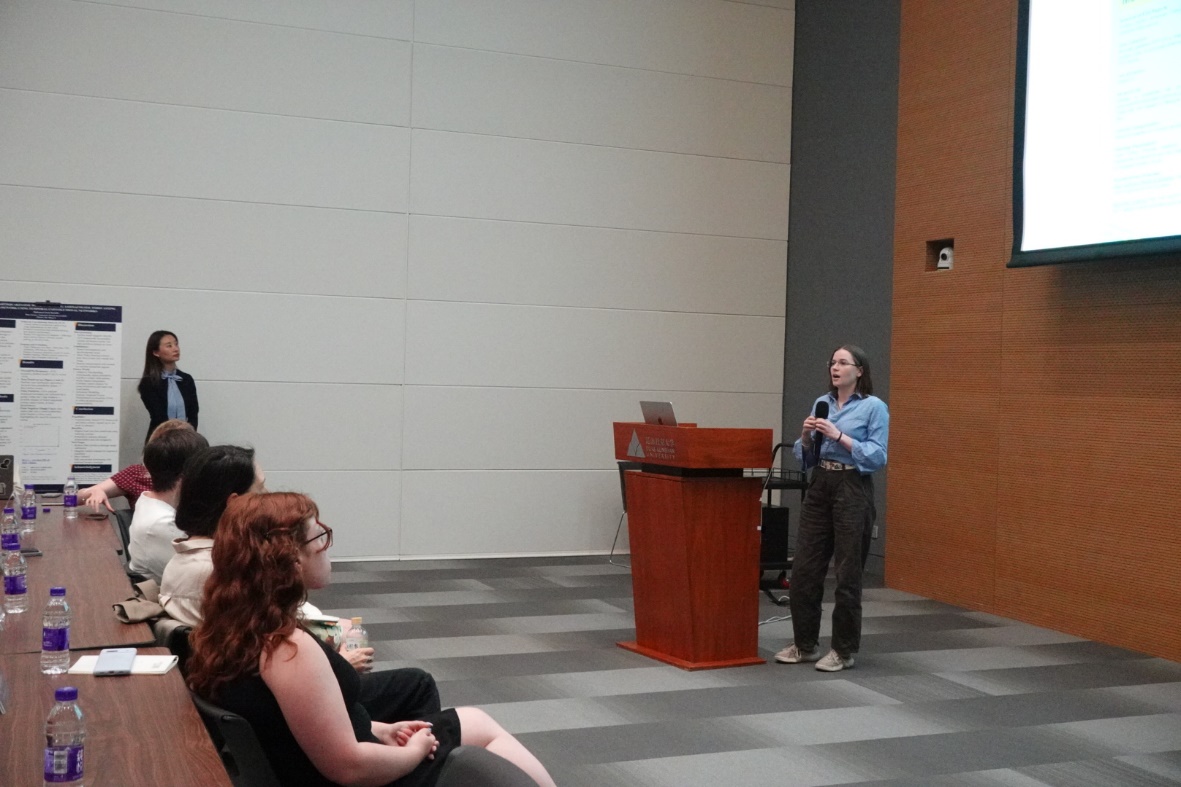 A person standing at a podium speaking to a group of people

Description automatically generated