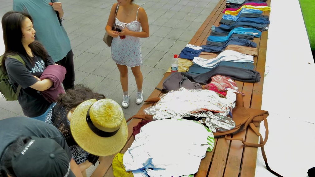 A group of people looking at clothing on a table

Description automatically generated